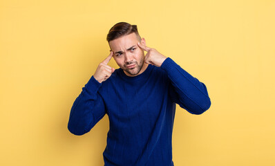 young handsome man looking concentrated and thinking hard on an idea, imagining a solution to a...