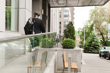 White senior man wearing leather backpack and scarf walking outdoors