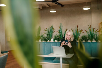 Smiling businesswoman using smart phone while sitting in coworking office