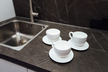 three empty white cups are on the kitchen table. pour fragrant morning coffee