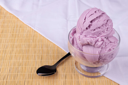Grape-flavored purple ice cream served in a bowl with a spoon on the side. White towel at the bottom crumpled diagonally folded. Gourmet Photography Ice Cream Shop