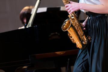 Fototapeta premium A performance of a saxophone player playing together with a pianist on a black grand piano
