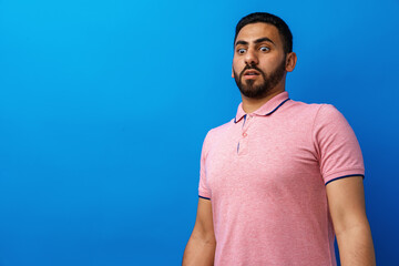 Young man nervous and scared looking at something against blue background