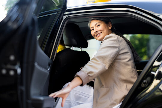 Smiling woman closing taxi door