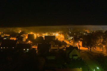 Fototapeta na wymiar Panorama małego miasteczka Iłowa położonego w Polsce. Jest noc. Ciemności rozświetla światło latarni. Widok z drona.