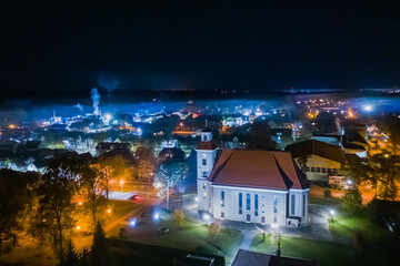 Kościół katolicki w mieście Iłowa w Polsce. Widok w nocy. Zdjęcie z drona. - obrazy, fototapety, plakaty