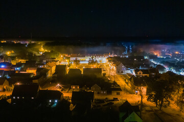 Panorama małego miasteczka Iłowa położonego w Polsce. Jest noc. Ciemności rozświetla...