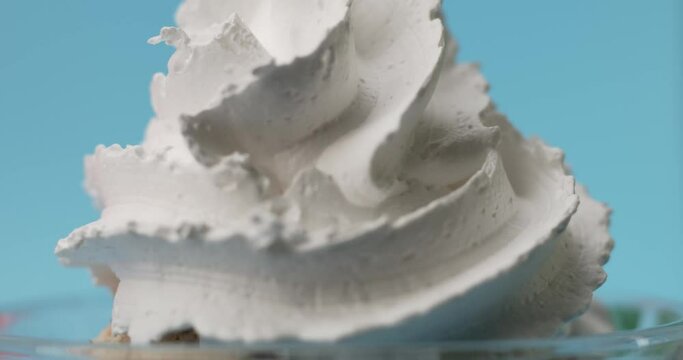 Close up, Chef squeezes white whipped cream onto cookie cream flavored ice cream. On the blue black ground.