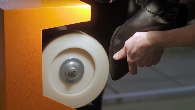 Close up: shoemaker, shoes master using automatic shoe polish machine tool for polishing black leather women footwear at workshop