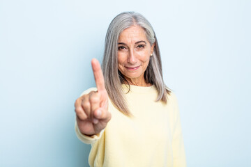 middle age gray hair woman smiling proudly and confidently making number one pose triumphantly,...