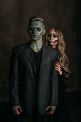 The image of a skeleton girl and the image of a Frankenstein man on Halloween in the dark. an image for a couple on Halloween. a woman holds onto a man's shoulder