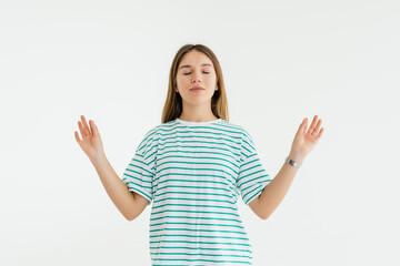 young woman meditating, holding her hands in yoga gesture, feeling calm and positive, isolated on white studio background, closed eyes