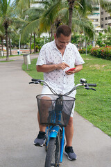 Older man checking his cell phone while riding his bike in the city