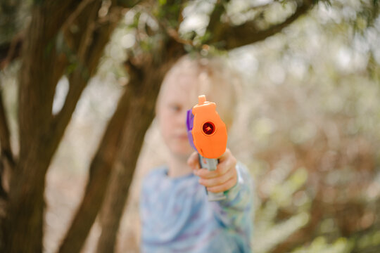 Boy holding toy nerf gun directly in front in backyard battle