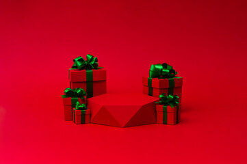 Red gift box with green ribbon and red pedestal on the red background. Christmas creative concept. Place for text.