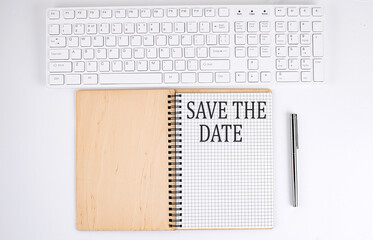 SAVE THE DATE text on the notebook with keyboard on white background