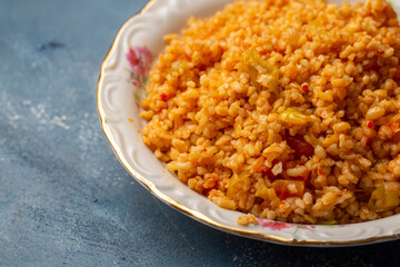 Traditional turkish bulgur pilaf with tomato sause in plate (Turkish name; meyhane pilavi)