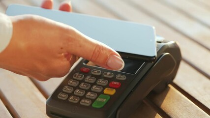 Contactless payment with smartphone. Wireless payment concept. Close-up, woman using smartphone cashless wallet NFC technology to pay order on bank terminal.