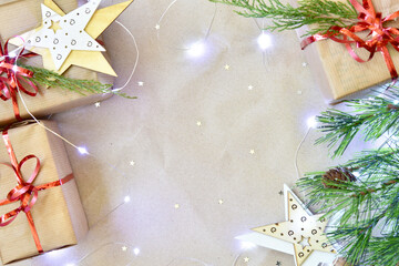gifts and scattered glitter stars on a beige craft paper background with lights. Christmas or New Year's layout. Рlace to add text.