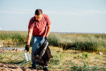Male environmentalist collecting protective face mask during sunny day