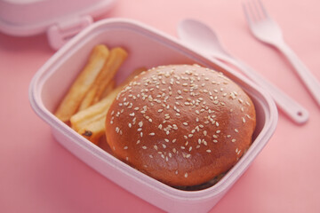 beef burger and french friend in a lunch box on pink background 