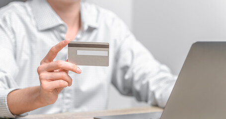 Woman using laptop and holding credit card in hands.