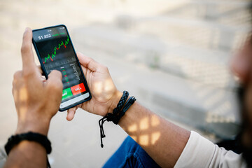 Man checking stock market graph through mobile phone