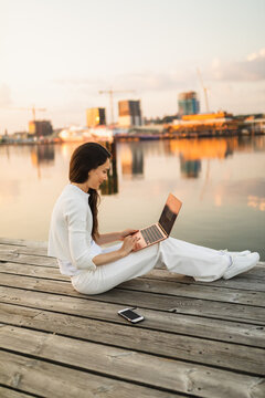 Cheerful woman browsing laptop on shore