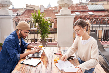 Focused woman writing in notebook at table with busy man