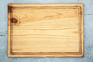 Top view of old chopping or cutting wooden kitchen board over gray background.