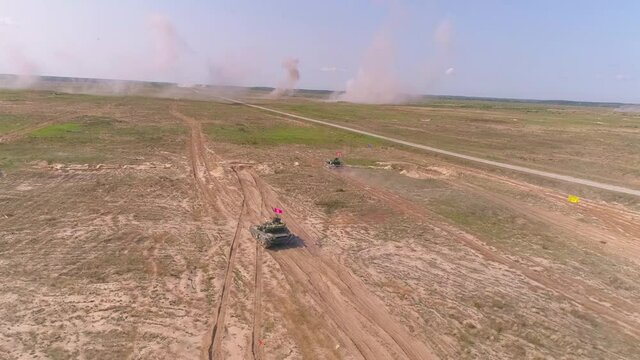 Army vehicle moving in sand and dust to protect innocent against aggression. Military heavy armored defense concept. T-64 tank shooting epic aerial view 4k UHD top down footage.