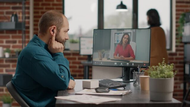Employee talking to manager using video call and earpods on computer at desk. Business man attending meeting with colleague to discuss marketing strategy on remote online video conference.