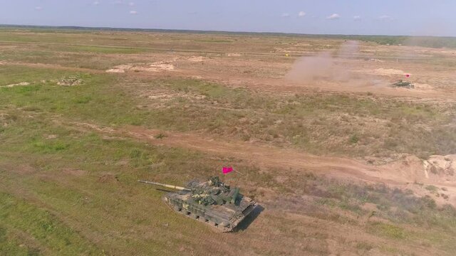 Cinematic slow-mo action footage of army tank shooting powerful canon in slow motion drone footage. Heavy armored military vehicle training to defend your way of life in dust and sand. Aerial view. 