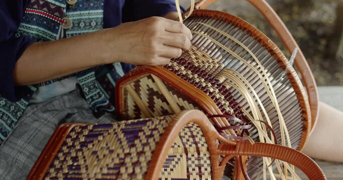 Cut in shot of Thai female farmer weave basket in traditional Thai art patterns to sell as extra income in countryside of Thailand