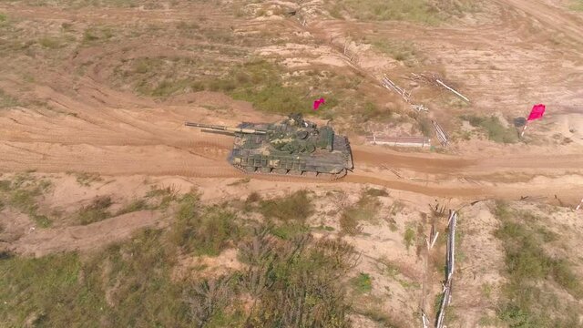 Epic slow-motion drone footage T-64 tank shot. Aerial view of heavy armored army vehicle training in sand. Ukrainian military hitting target with powerful cannon creating lots of dust. 4k UHD motion
