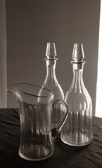 Vintage background. Two antique glass bottles and a carafe on a table. Dark image, sepia colors. Vertical artistic image