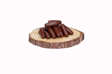 Brown Drug capsule put on a small wooden cutting board isolated on white background. Medicine is a capsule pill. Vitamin strengthens immune system. Body's immune response after the vaccine is good. 