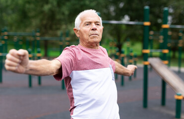 Elderly man doing gymnastic exercises in park