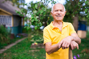 Naklejka na ściany i meble Senior man with shovel standing in yard of his house