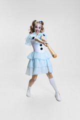 Halloween spooky theme. Portrait of beautiful artistic girl in halloween make-up and costume of dancing clown isolated over grey background