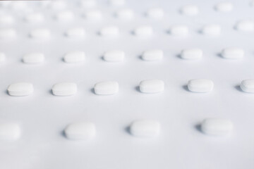Many white pills on a white background. Health.	
