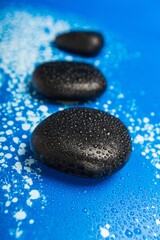 Row of black stone pebbles on water drops