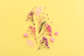 Top view image of pink, purple and green flowers composition over pastel yellow background .Flat lay