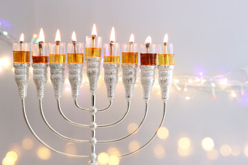 Image of jewish holiday Hanukkah with menorah (traditional candelabra) and oil candles over garland...