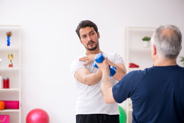 Young male instructor and old man doing sport exercises