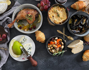 French dishes and appetizers served on dark background.
