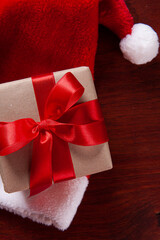 Christmas composition with gift and Santa hat on wooden background.Top view with copy space