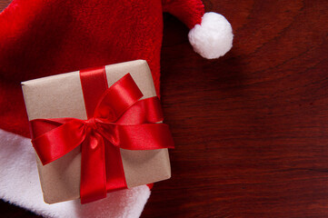 Christmas composition with gift and Santa hat on wooden background.Top view with copy space