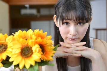 Naklejka premium 古民家の和室にて白いワンピースを着て微笑む若い女性とひまわり