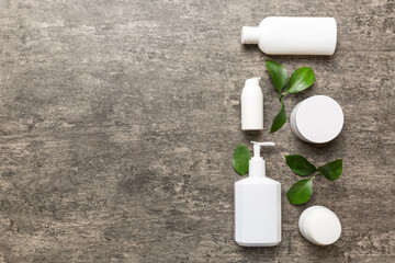 Organic cosmetic products with green leaves on cement background. Copy space, flat lay